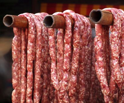 Handmade sausages at a local outdoor butcher hang on bamboo poles