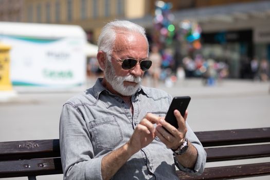 Old man use internet application on smartphone, urban city background stock photo
