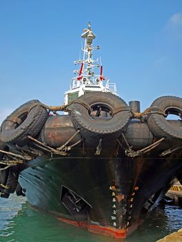 A single tugboat with massive fastened to the hull
