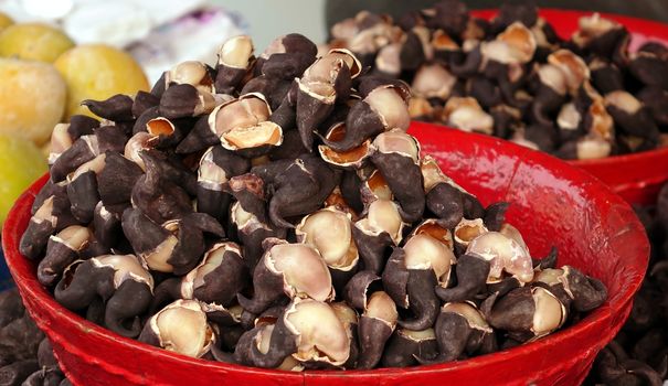 An outdoor vendor sells Chinese water chestnuts in red basins
