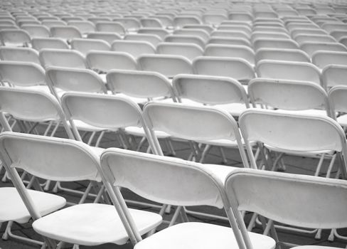 Rows of plastic chairs are set up for an outdoor  performance

