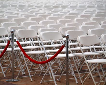 Rows of plastic chairs are set up for an outdoor concert
