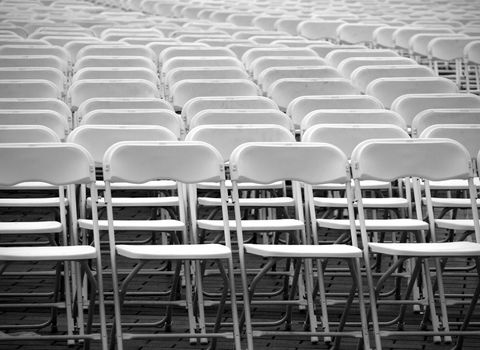 Rows of plastic chairs are lined up for an outdoor concert
