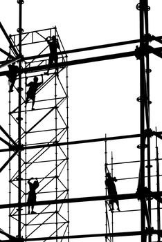 Construction workers in silhouette high up on a stage setup
