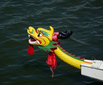 A decorated dragon boat with a yellow dragon head and red sash