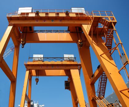 Two yellow overhead gantry cranes with Chinese writing that says - Safety First-.