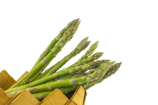 Bundle of fresh green asparagus in a rustic woven basket isolated on white background, selective focus in a low angle view
