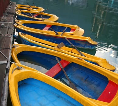 Blue and yellow rowboats are tied to a wooden pier