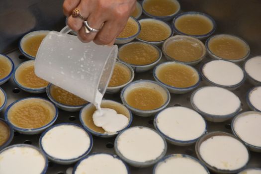 process of making coconut milk custard in small porcelain cup (Thai dessert).