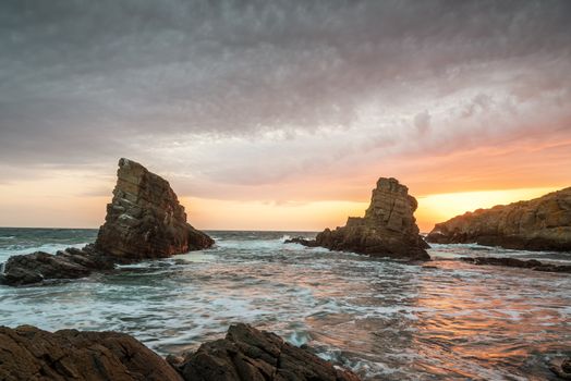 Dramatic sunrise with mist on the beach with rocks.