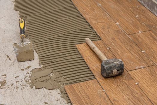 Ceramic tiles and tools for tiler. Floor tiles installation. Home improvement, renovation - ceramic tile floor adhesive, mortar, level.