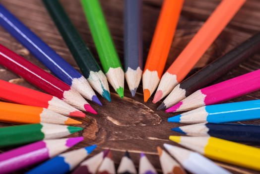 Colored multi colored pencils close up macro down on a vintage wooden background.