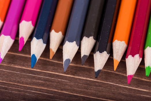 Colored multi colored pencils close up macro down on a vintage wooden background.