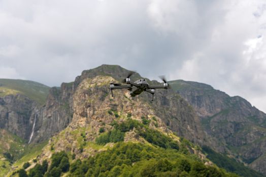 Drone with camera flying over mountain fields. Aerial photography and videography.