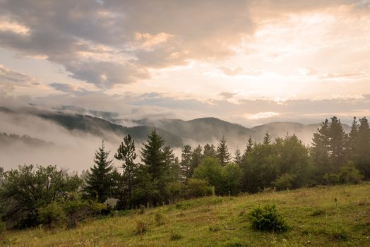 Amazing mountain landscape with colorful vivid sunset at fog.