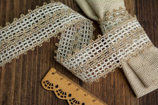 knitted beige openwork linen ribbon tapes in rural style of rustics cotton eco natural on wood ground
