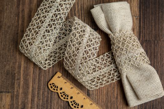 knitted beige openwork linen ribbon tapes in rural style of rustics cotton eco natural on wood ground