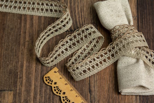 knitted beige openwork linen ribbon tapes in rural style of rustics cotton eco natural on wood ground