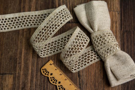 knitted beige openwork linen ribbon tapes in rural style of rustics cotton eco natural on wood ground