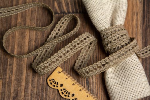 knitted beige openwork linen ribbon tapes in rural style of rustics cotton eco natural on wood ground