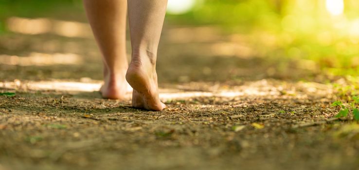bare feet of a woman walking along a trail in the woods.