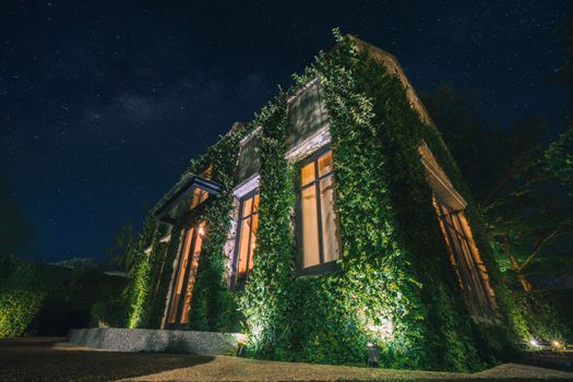 Beautiful starry sky and English country style building covered with green creeper plant 