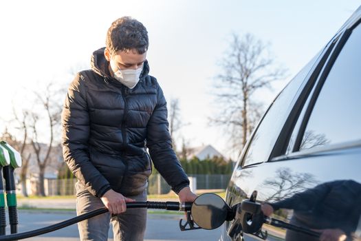 fueling the car at the time of the epidemic coronavirus with a respirator over his mouth and nose.