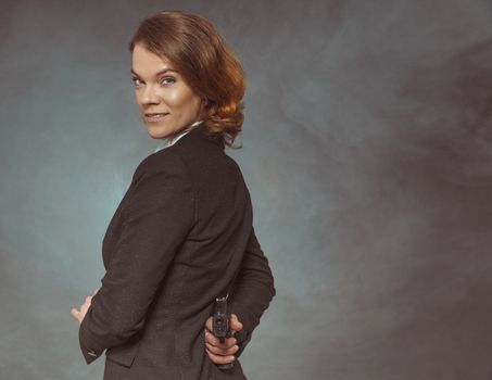 Portrait of woman with gun on grey background