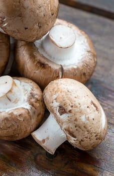 Closeup of fresh brown champignons mushrooms, Agaricus bisporus, on wood