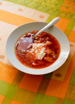 Simple traditional homemade red Ukrainian Borscht with smetana cream in a white porcelain plate