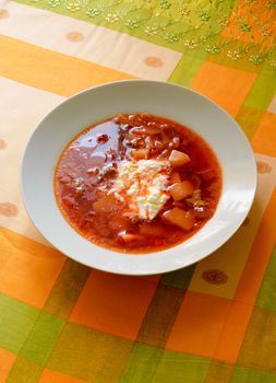 Simple traditional homemade red Ukrainian Borscht with smetana cream in a white porcelain plate