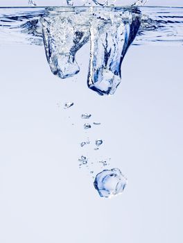 Ice cubes falling in clear water, with bubbles