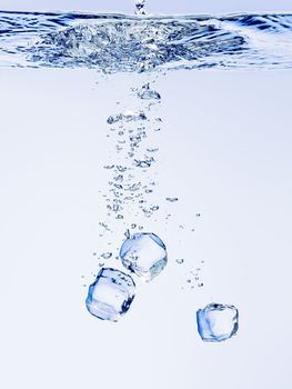 Ice cubes falling in clear water, with bubbles