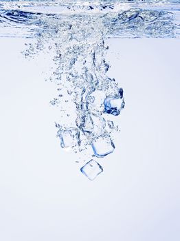 Ice cubes falling in clear water, with bubbles