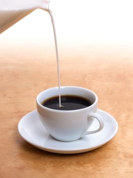 Pouring fresh milk in warm coffee