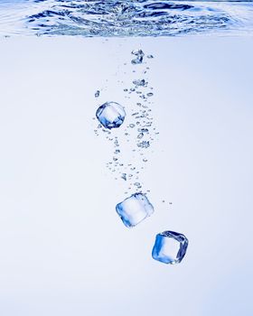 Ice cubes falling in clear water, with bubbles