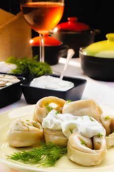 Russian dumplings (pelmeni) with  sour cream (smetana) and fennel, on a rich table
