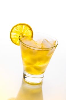 A fresh and tasty cocktail with alcohol and lemon on a glass table with yellow reflection