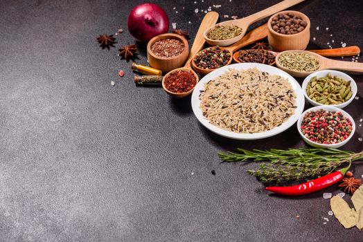 A set of spices and herbs. Indian cuisine. Pepper, salt, paprika, basil and other on a dark background. Top view. Free copy space.