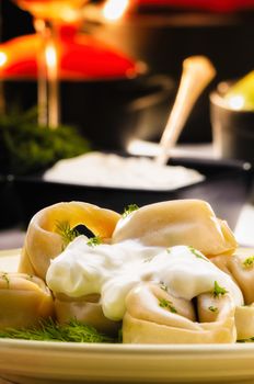 Russian dumplings (pelmeni) with  sour cream (smetana) and fennel, on a rich table