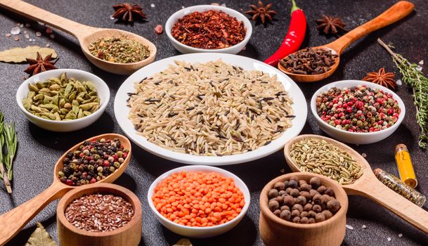 A set of spices and herbs. Indian cuisine. Pepper, salt, paprika, basil and other on a dark background. Top view. Free copy space.