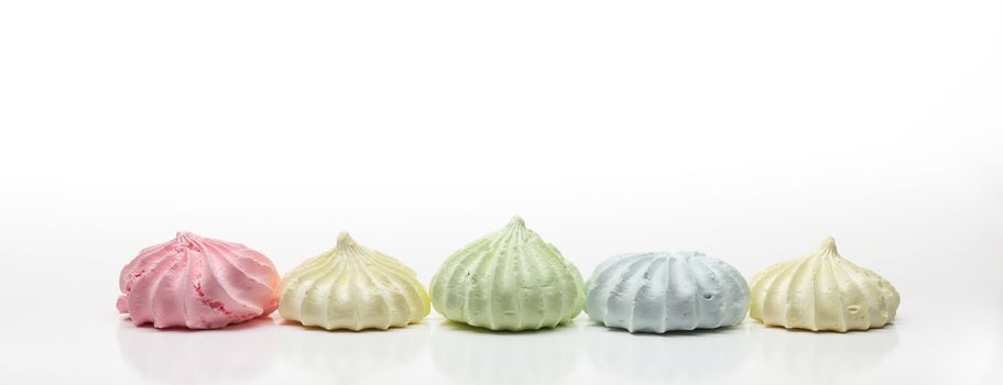 Five colored french meringues aligned in a row, on white background