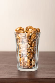 Fresh peeled walnuts in a glass on a wooden table, with negative space for copy text