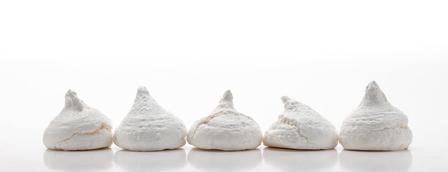 Five white french meringues aligned in a row, isolated on white background