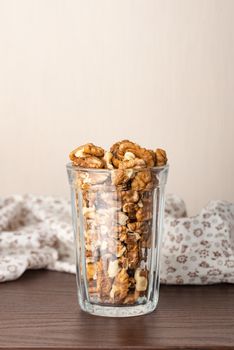 Fresh peeled walnuts in a glass on a wooden table with a white flowery tablecloth, and negative space for copy text