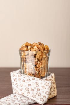 Fresh peeled walnuts in a glass on a wooden table with a white flowery tablecloth, and negative space for copy text