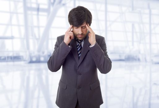 Businessman in a suit gestures with a headache, at the office