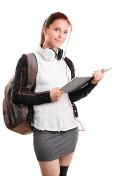 Beautiful smiling young girl in schoolgirl uniform with backpack and headphones, holding an open book, isolated on white background. Student ready for class. Education concept.