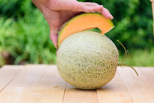 The man use knife split the orange melon on wood plate