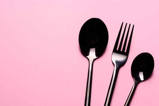 Metal Spoon and fork Isolated on pink background. Set of tableware ready for the meal with pink copy space